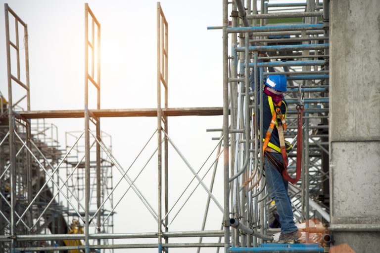 Trabajador utilizando un andamio metálico durante actividades en una obra de construcción