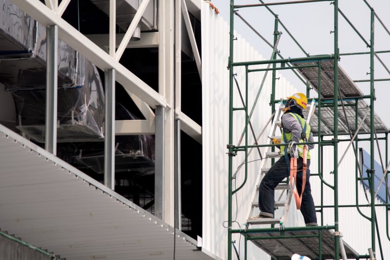 Trabajador utilizando un andamio metálico para realizar trabajos en altura en una instalación industrial