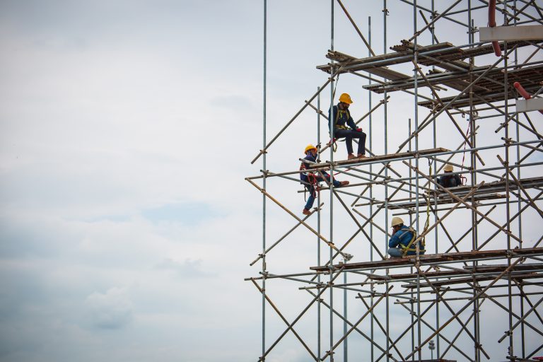 Trabajador realizando labores de montaje de andamios en una estructura industrial